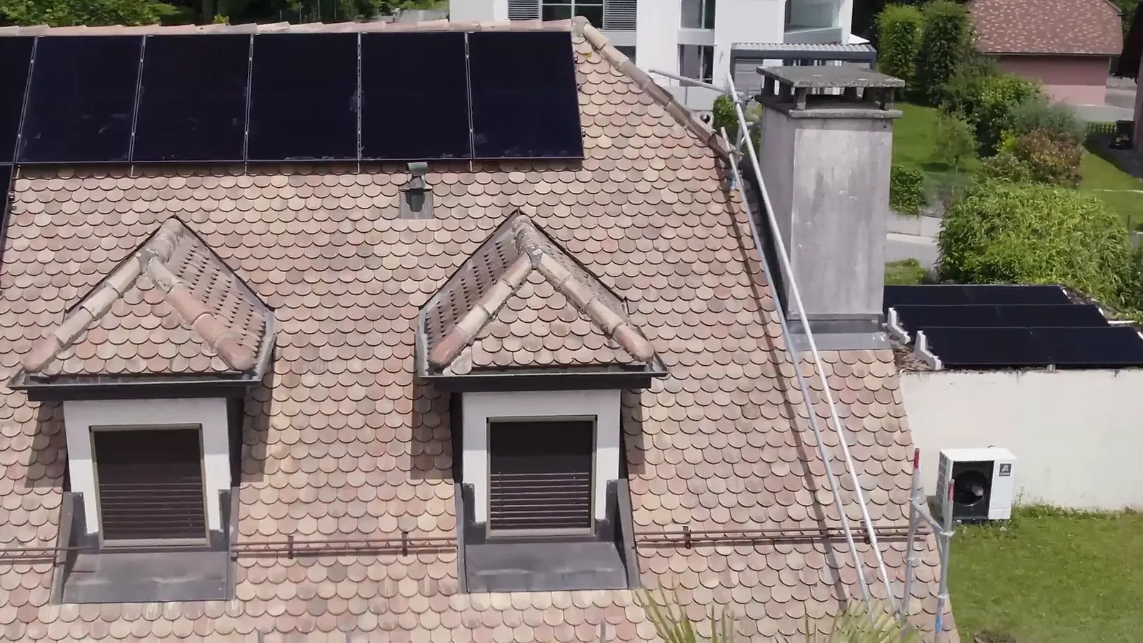 Survol d'une toiture à lucarnes équipée de panneaux solaires