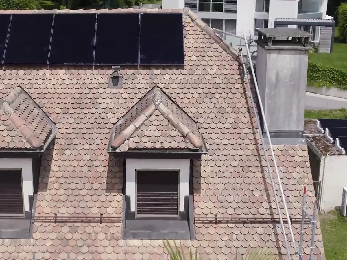 Toiture avec lucarnes et cheminée, panneaux solaires posés autour des obstacles