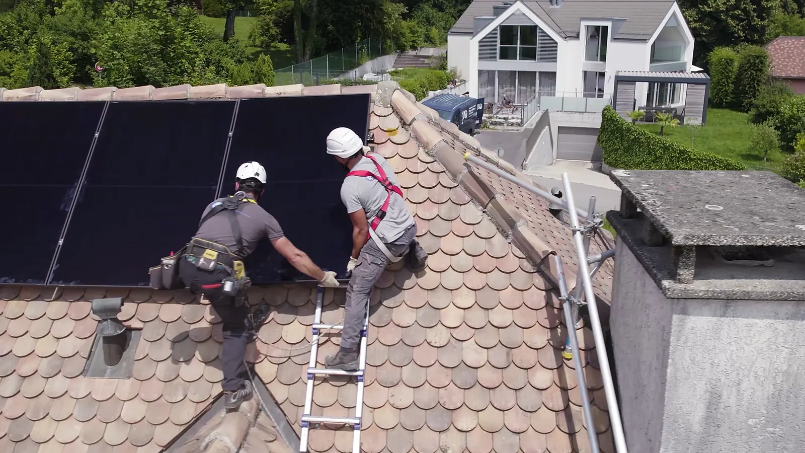 Technicien posant un panneau solaire sur une toiture en tuiles, photo de chantier