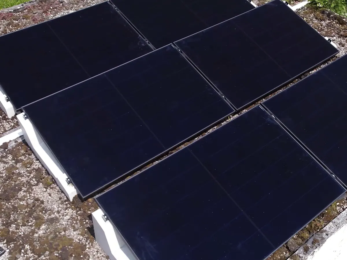 Panneaux solaires noirs posés sur plots lestés, toiture plate