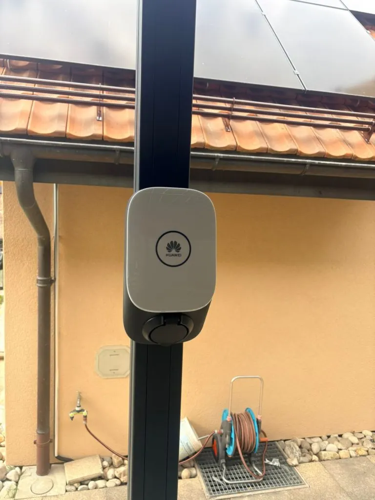 Toit en tuiles d'une villa genevoise avec panneaux solaires noirs en surimposition, quartier résidentiel