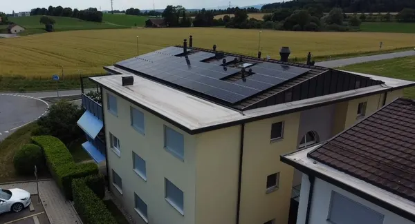 Immeuble résidentiel à toit plat avec panneaux solaires, champs de céréales alentour.