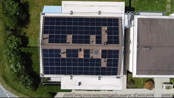 Vue aérienne d'une toiture plate industrielle entièrement couverte de panneaux solaires noirs.
