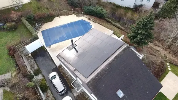 Vue aérienne d'une villa avec piscine couverte, toiture ardoisée entièrement couverte de panneaux.